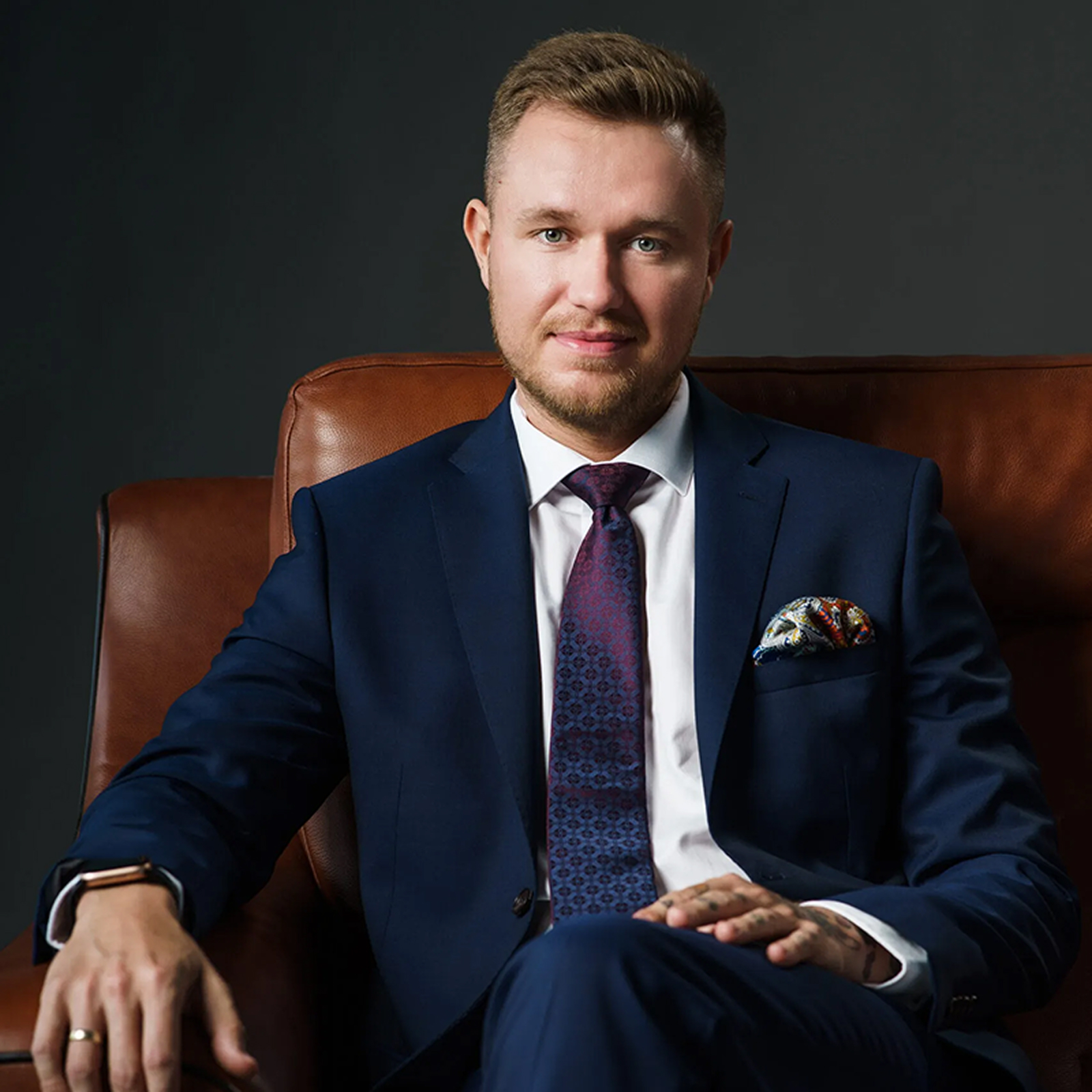 Michal Lesiak ubrany w garnitur, siedzi na 